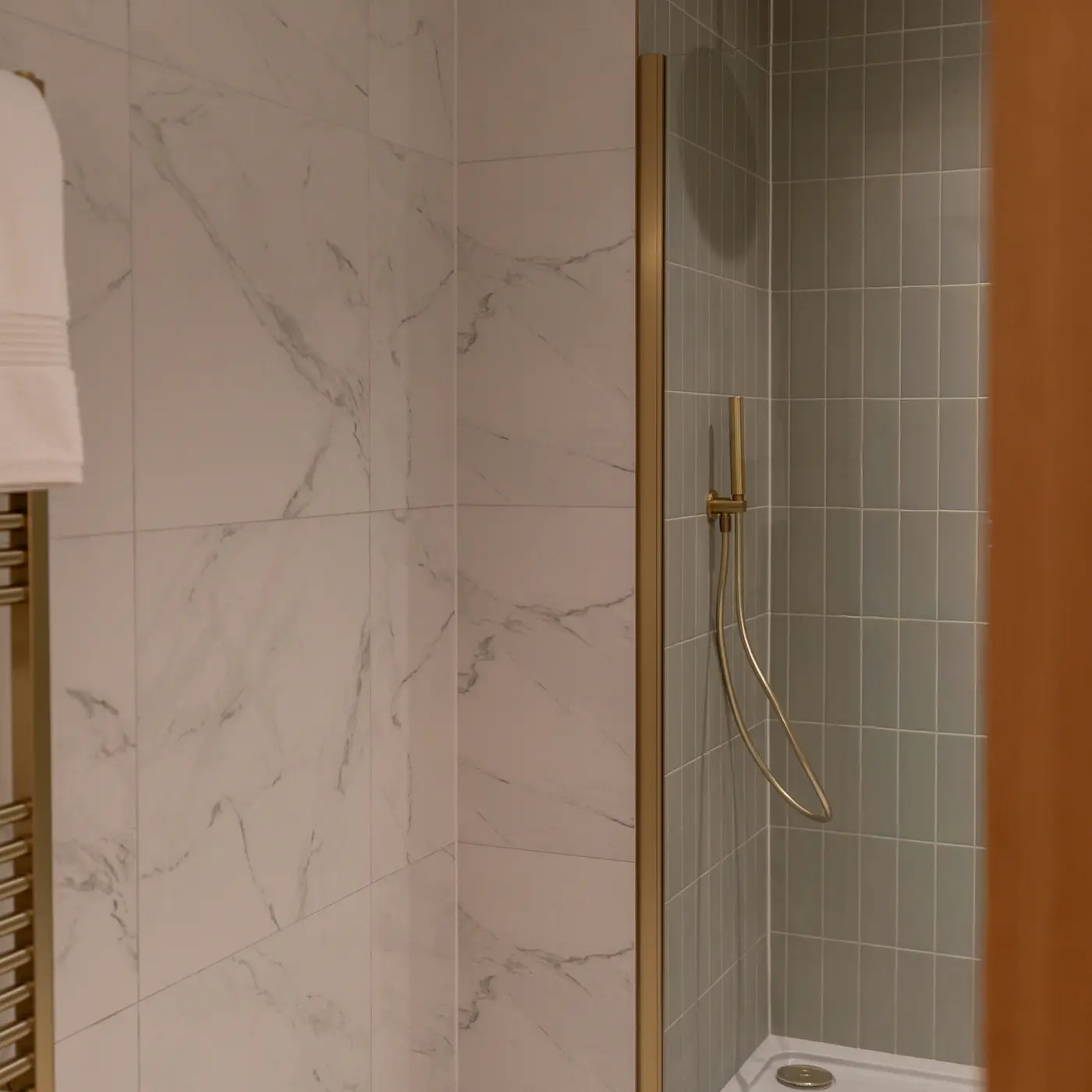 Shot of the ensuite on the main bedroom, marble tiling with gold feature finishes and sage green tiling within the shower